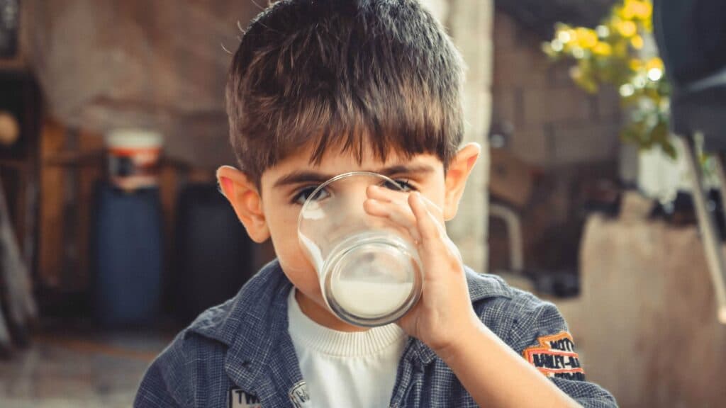 Niño que usa un vaso para tomar leche